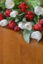 Red and white tulips on a wooden table. 
