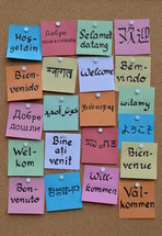 welcome in various languages on sticky notes on a cork board 