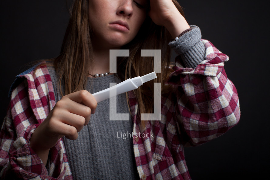 a teen girl holding a pregnancy test 