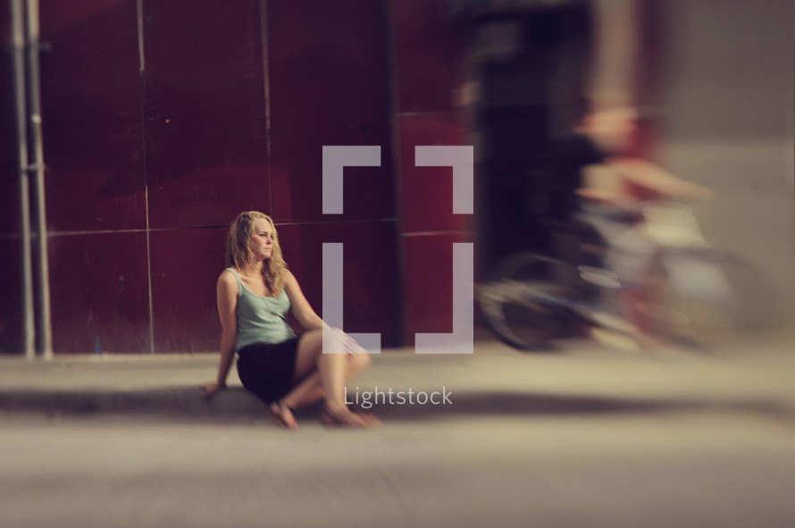 woman sitting on a sidewalk 