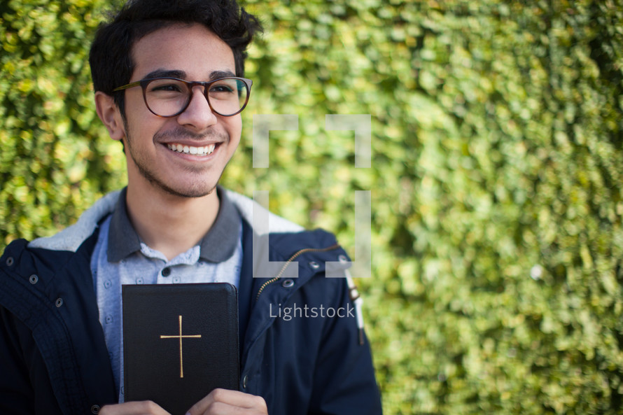 smiling man holding a Bible outdoors 