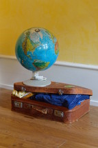 a globe on a stuffed suitcase 