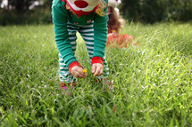 child in elf pajamas picking flowers 