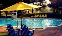 lawn chairs and umbrellas around a swimming pool 