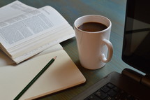 open Bible, journal, pencil, mug of coffee, and laptop on a desk 