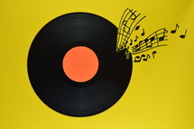 old black vinyl record with blank orange label centered on yellow background with notes and staves coming from it