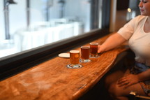 a woman at a bar with a flight of beer 