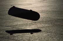 skater jumping on his skateboard with his shadow in evening backlight.
