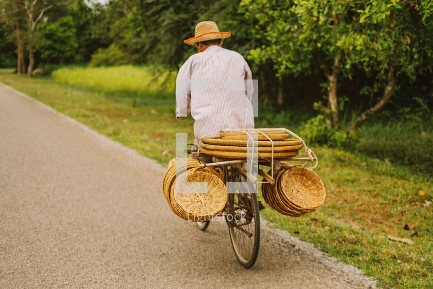 A man riding a bicycle carrying straw baskets