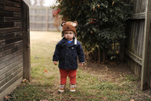 a toddler boy in a jacket and cap 