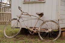 An old bicycle leaning against a shed.