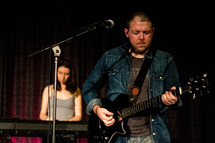 man playing a guitar and a woman on a keyboard 