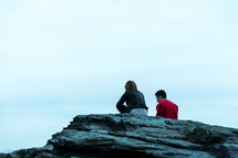 couple sitting on top of a rock 