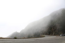 curve on a mountain highway through fog 