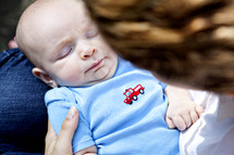 An infant sleeping in his mother's arms.