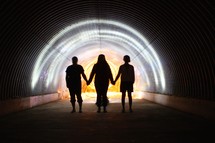 people holding hands in a dark tunnel 