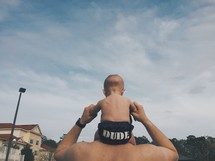 a baby on his father's shoulders wearing a dude diaper cover 