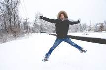 man in fur lined coat jumping in snow 