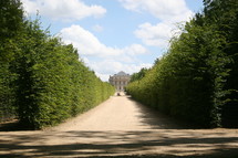 long dirt driveway leading to a chateau 