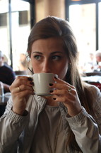 a woman sipping from a mug 