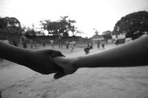 Black and white children holding hands  while playing a game.