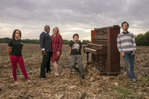 family standing next to an old piano outdoors 