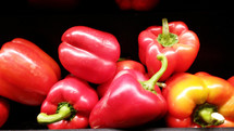 Seven ripe red peppers with green stalks against a black background ready to be added to a barbecue, taco or salad to make a delicious meal for picnics, dinner or summertime snack. 