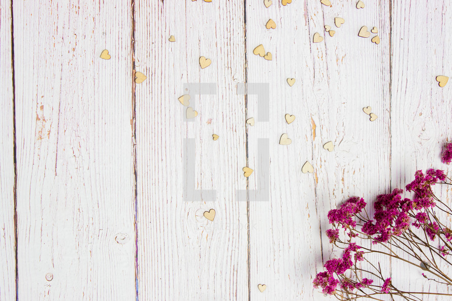 pink flowers, and wood hearts on a white wood background 