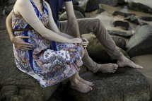 a couple holding hands sitting on rocks 