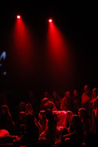 performers dressed as shepherds sitting on stage under the glow of red light