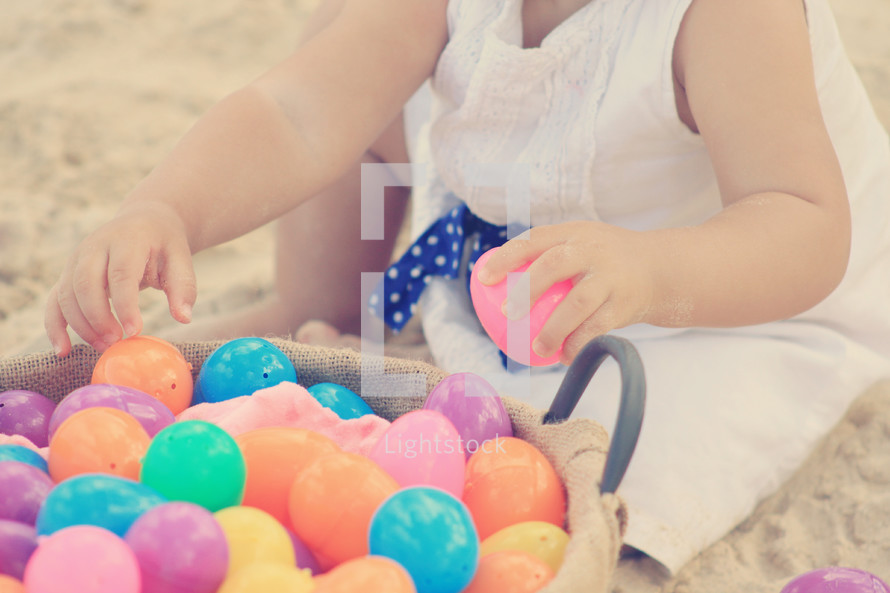 Child's hands holding Easter eggs in a basket.