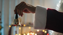 Santa ringing a small bell with his hand
