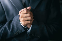 praying hands of a male in a suit 