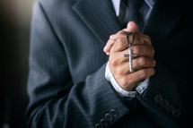 a praying man in a suit holding a cross