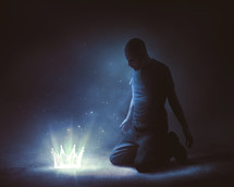 man kneeling before a glowing crown 
