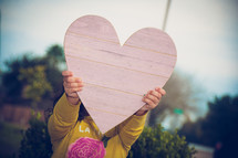 a child's hand up a wooden heart