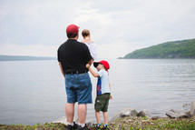 a father and his children standing on a lake shore 