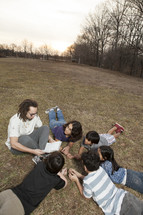 a young man reading a Bible to a group of kids 