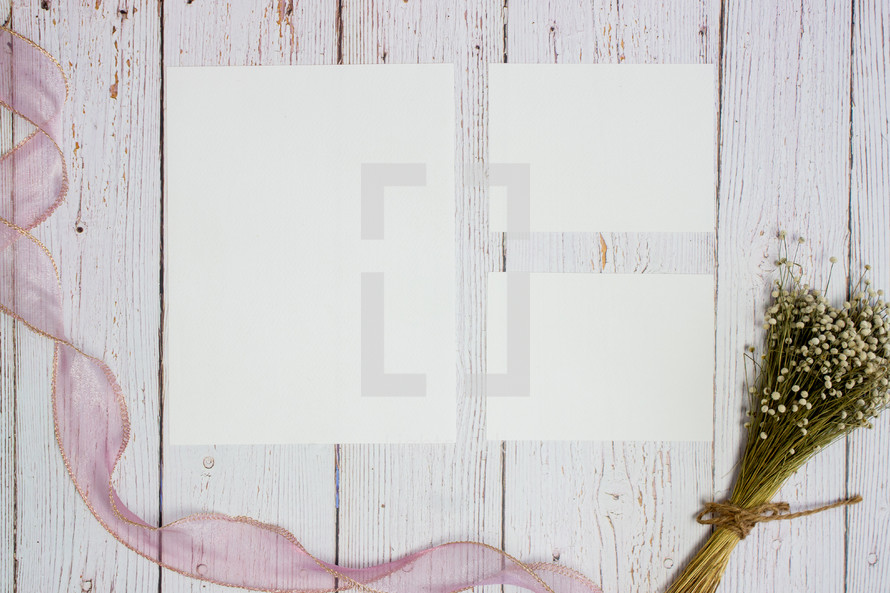 blank white paper on a white wood background with dried flower bouquet 