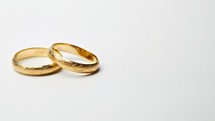 Two gold wedding rings on white background with copy space for text.