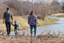 a family walking outdoors along a river bank in fall 