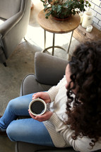 a woman sitting in a chair with a cup of coffee 
