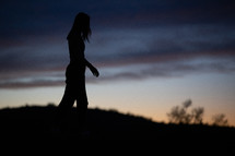 silhouette of a young woman on a mountaintop at sunset 