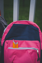 pink and gray book bags with pencils in the pockets