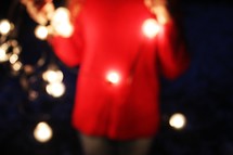 a woman holding a strand of Christmas lights 