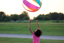 a girl child bouncing a beach ball 
