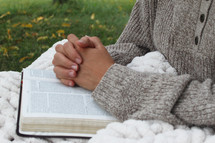woman reading a Bible outdoors in fall under a blanket 