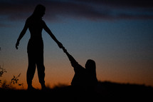 silhouettes of young women on a mountaintop at sunset 