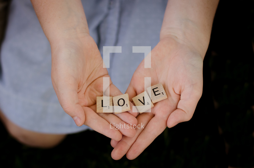 a woman holding scrabble pieces with the word love 