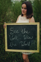 woman holding a sign - see the world win the world 